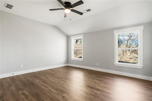 unfurnished room featuring lofted ceiling, dark wood-type flooring, visible vents, and baseboards