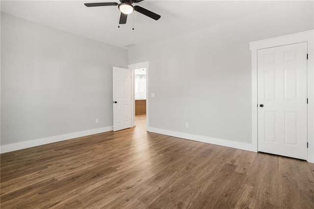 unfurnished room with ceiling fan, baseboards, and dark wood-style flooring