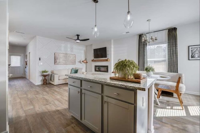235 Ivey Ter, Temple, GA 30179 - kitchen featuring gray cabinetry, light wood-style flooring, open floor plan, pendant lighting, and light stone counters