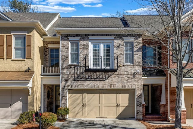 multi unit property featuring a garage, a shingled roof, concrete driveway, and brick siding