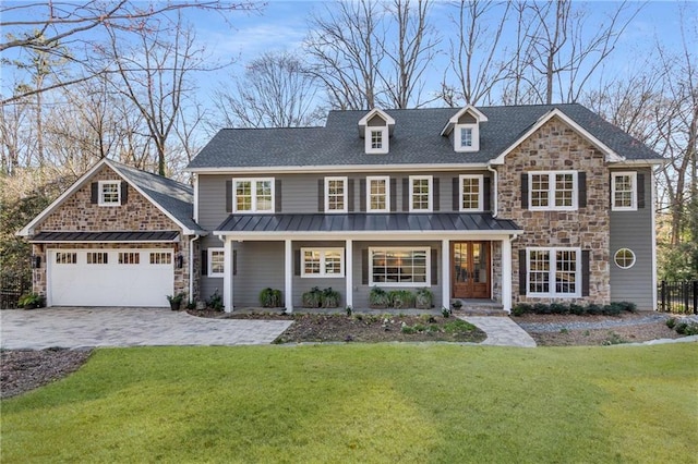 view of front of house featuring a front lawn, decorative driveway, a garage, stone siding, and a standing seam roof