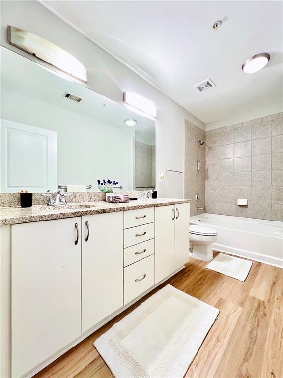 400 W Peachtree St NW Unit 2704, Atlanta, GA 30308 - full bathroom with double vanity, wood finished floors, and shower / bath combination