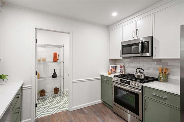 kitchen featuring appliances with stainless steel finishes, dark hardwood / wood-style flooring, green cabinets, white cabinets, and decorative backsplash