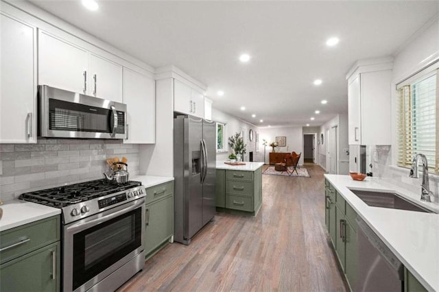 kitchen featuring appliances with stainless steel finishes, sink, green cabinets, white cabinetry, and light hardwood / wood-style flooring