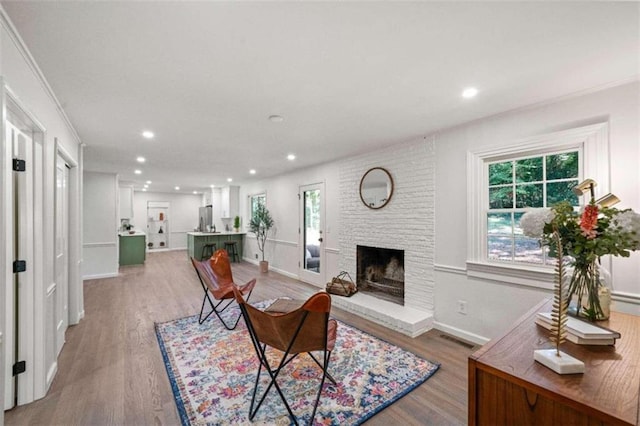 living room featuring light hardwood / wood-style floors, ornamental molding, and a fireplace