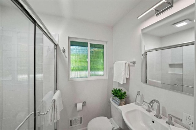 bathroom with a shower with door, toilet, and sink