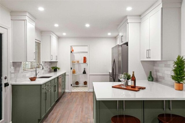 kitchen featuring a breakfast bar, light hardwood / wood-style flooring, stainless steel appliances, and green cabinets