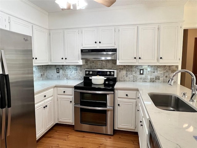 1461 Fox Forest Ter SW, Lilburn, GA 30047 - kitchen featuring appliances with stainless steel finishes, under cabinet range hood, a sink, white cabinets, and ornamental molding