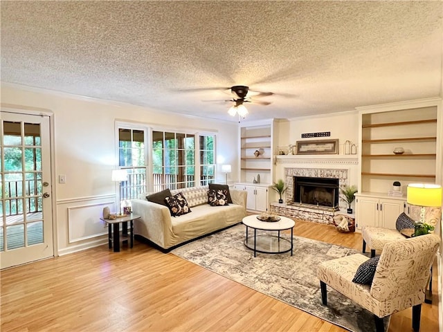 1461 Fox Forest Ter SW, Lilburn, GA 30047 - living room with a textured ceiling, ceiling fan, ornamental molding, a fireplace, and light wood-style flooring