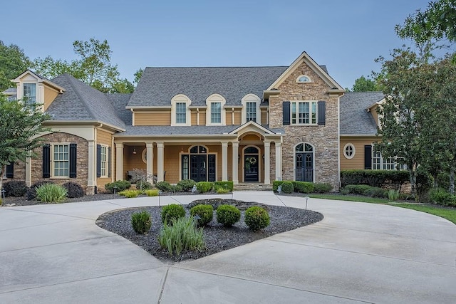 6225 Random Winds Blf, Gainesville, GA 30506 - view of front facade featuring stone siding, roof with shingles, curved driveway, and a porch