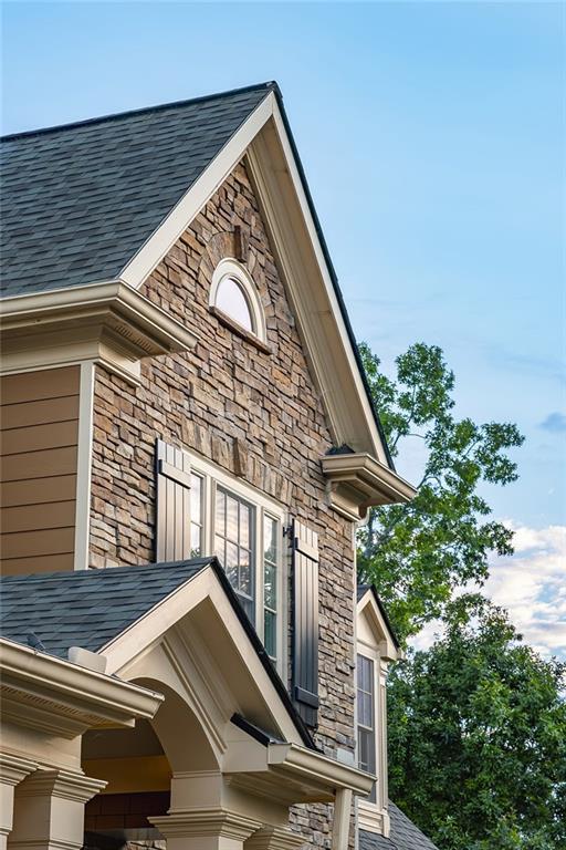 6225 Random Winds Blf, Gainesville, GA 30506 - exterior view of stone siding, roof with shingles, and gutters