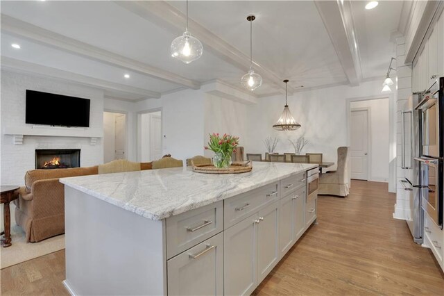 2620 Middle Coray Cir, Marietta, GA 30066 - kitchen with beam ceiling, light stone counters, a kitchen island, light wood-style floors, and white cabinets