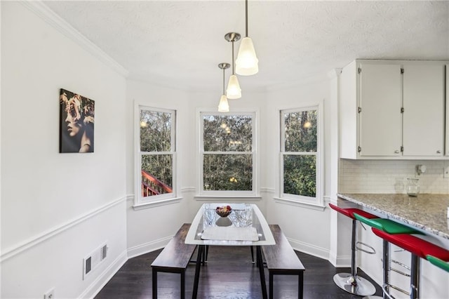 dining room featuring a textured ceiling, a healthy amount of sunlight, dark hardwood / wood-style flooring, and crown molding