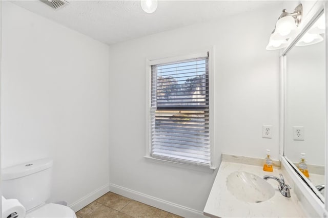 bathroom with toilet, vanity, and tile patterned flooring