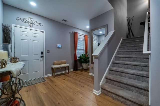 entrance foyer with stairs, wood finished floors, visible vents, and baseboards