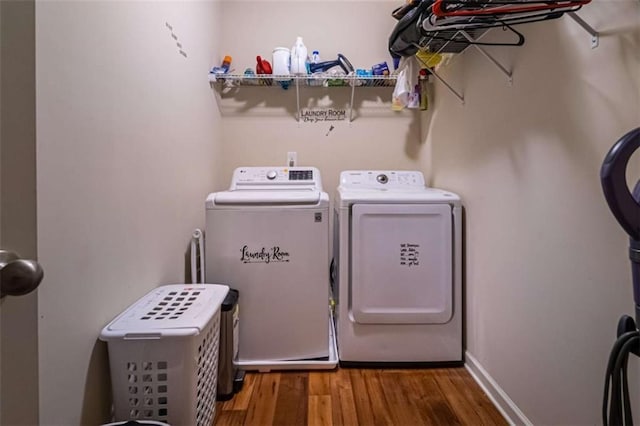 washroom with laundry area, wood finished floors, baseboards, and washing machine and clothes dryer