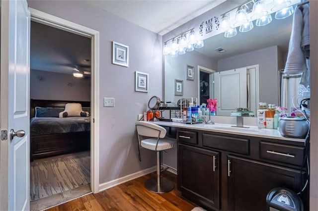 bathroom featuring vanity, wood finished floors, baseboards, and ensuite bathroom