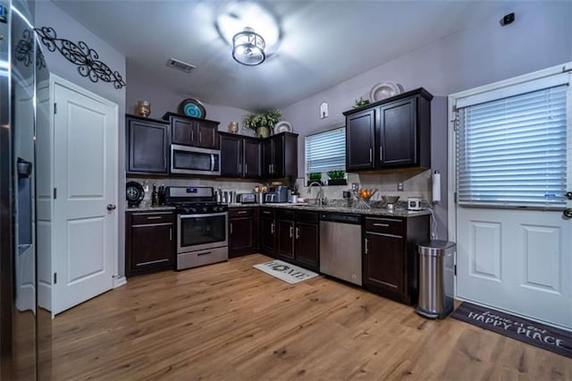 kitchen with light wood finished floors, visible vents, backsplash, appliances with stainless steel finishes, and a sink