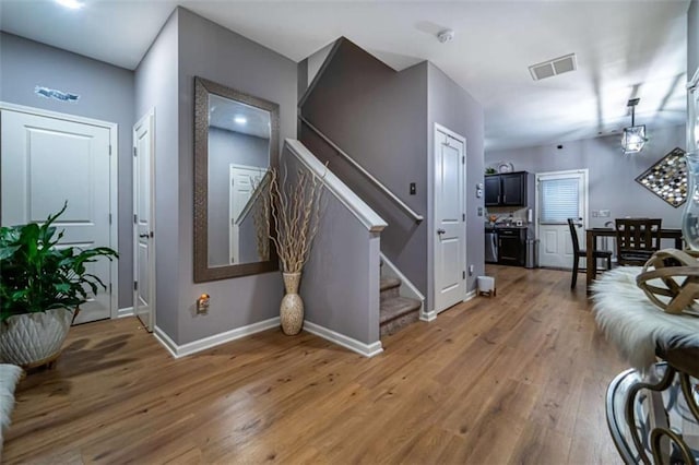 living area featuring visible vents, light wood-style flooring, stairs, and baseboards