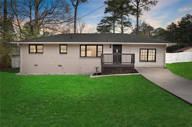 ranch-style house with a wooden deck and a lawn