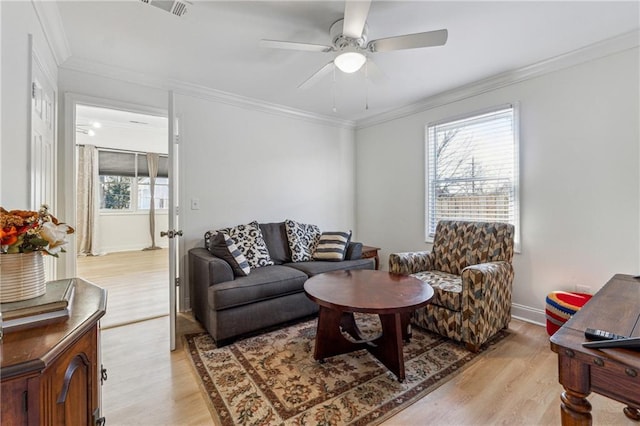 living room with a wealth of natural light, crown molding, and light hardwood / wood-style flooring