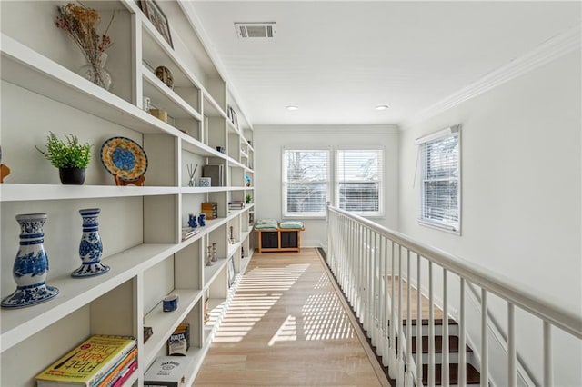 hallway featuring ornamental molding and light hardwood / wood-style floors