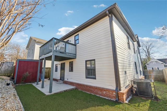 back of house featuring central air condition unit, a storage unit, a lawn, and a patio