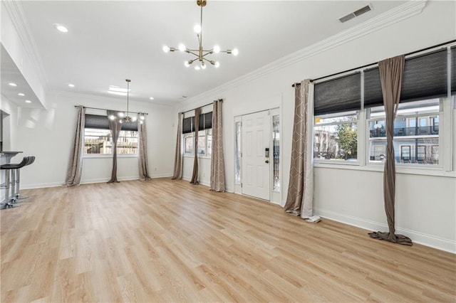 unfurnished living room featuring light hardwood / wood-style flooring, ornamental molding, and an inviting chandelier