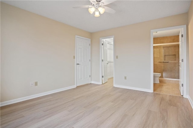 unfurnished bedroom featuring a walk in closet, light wood-type flooring, ensuite bath, ceiling fan, and a closet