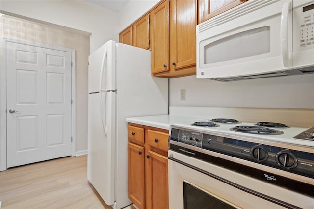 kitchen with white appliances and light hardwood / wood-style flooring