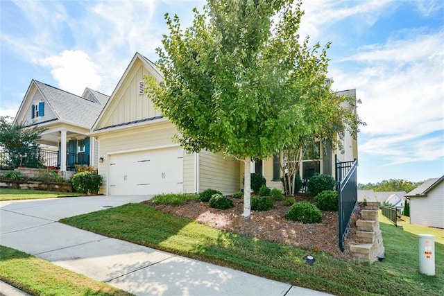 view of property hidden behind natural elements featuring a front yard, a garage, and covered porch