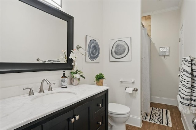 bathroom featuring toilet, vanity, crown molding, wood finished floors, and baseboards