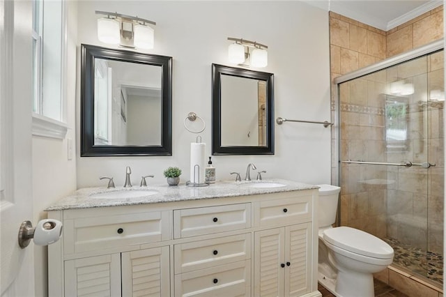 bathroom featuring a stall shower, toilet, double vanity, and ornamental molding