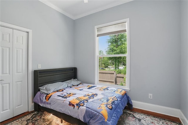 bedroom with wood finished floors, ornamental molding, a closet, and baseboards