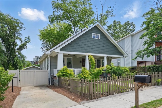 view of front of property featuring covered porch, a gate, a fenced front yard, concrete driveway, and ceiling fan