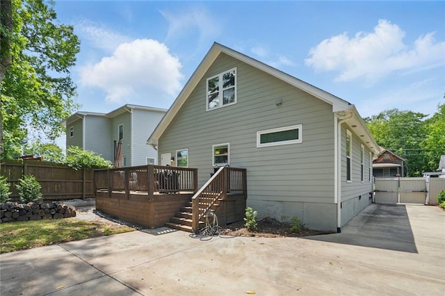 back of property with fence, a patio, a wooden deck, and concrete driveway