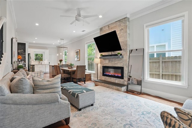 living area with crown molding, a fireplace, recessed lighting, a ceiling fan, and wood finished floors