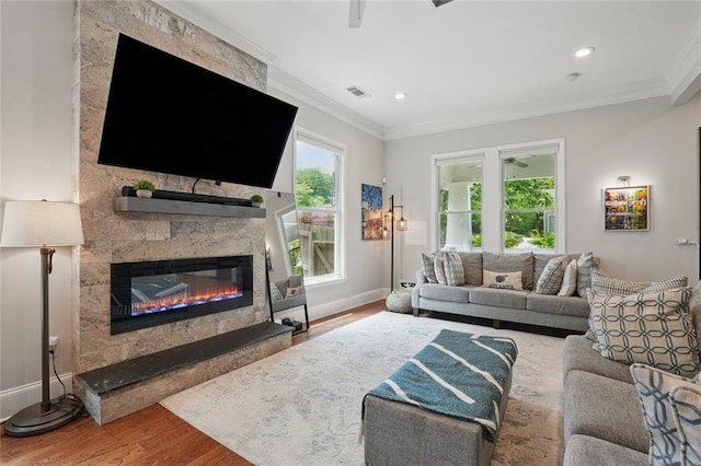 living area with wood finished floors, crown molding, a fireplace, baseboards, and recessed lighting