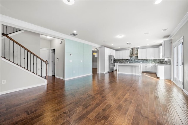 unfurnished living room featuring stairway, visible vents, dark wood-style flooring, and ornamental molding