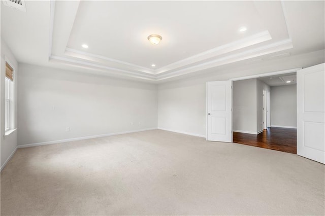 carpeted empty room with a raised ceiling, recessed lighting, baseboards, and visible vents