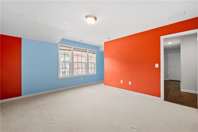 carpeted spare room featuring visible vents and baseboards