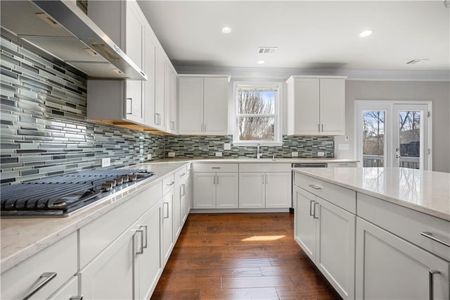 kitchen featuring a healthy amount of sunlight, visible vents, ornamental molding, stainless steel gas stovetop, and wall chimney range hood