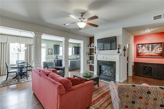 living room with hardwood / wood-style floors, ceiling fan with notable chandelier, and built in shelves