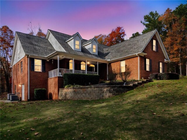 new england style home with a porch, a garage, and a front lawn