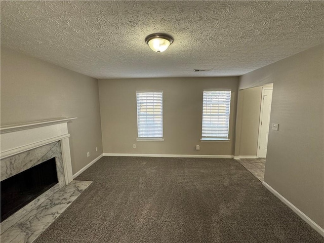 unfurnished living room with a high end fireplace, a textured ceiling, and carpet