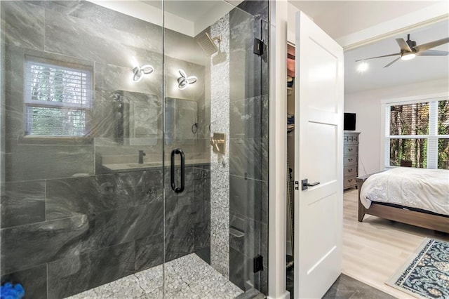 bathroom with a shower with shower door, hardwood / wood-style floors, and ceiling fan