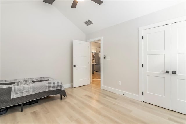 bedroom featuring stainless steel fridge, ceiling fan, light wood-type flooring, a closet, and lofted ceiling