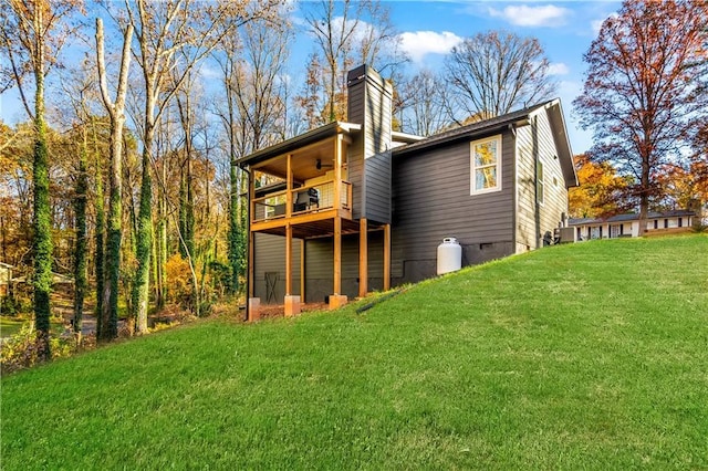 rear view of house featuring ceiling fan, a lawn, and a balcony