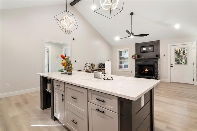 kitchen featuring a kitchen island, hanging light fixtures, light wood-type flooring, light stone countertops, and gray cabinetry