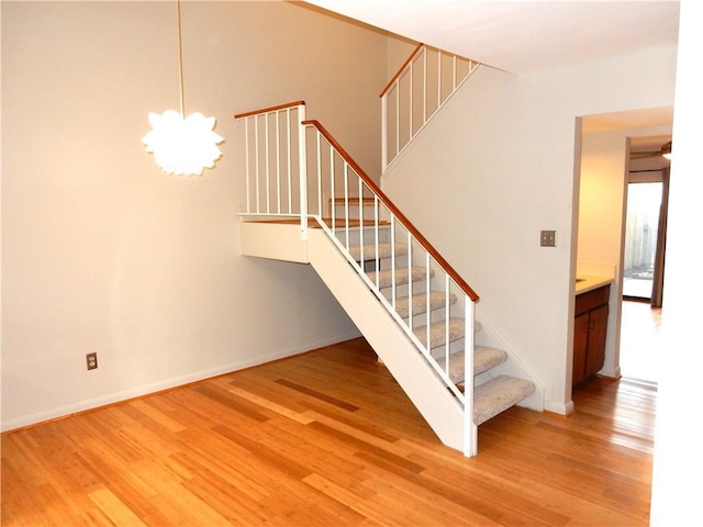 stairway with a notable chandelier and wood-type flooring